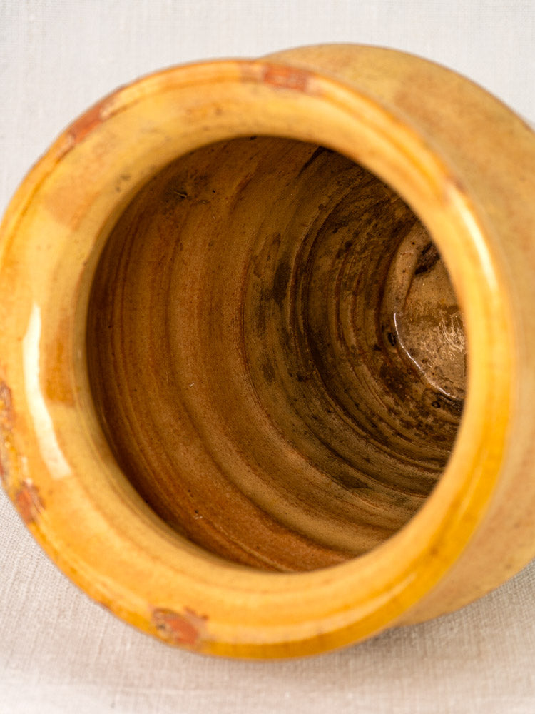 Antique French confit pot with yellow-glazed terracotta, spiraled interior, glossy finish, and slight rim wear.
