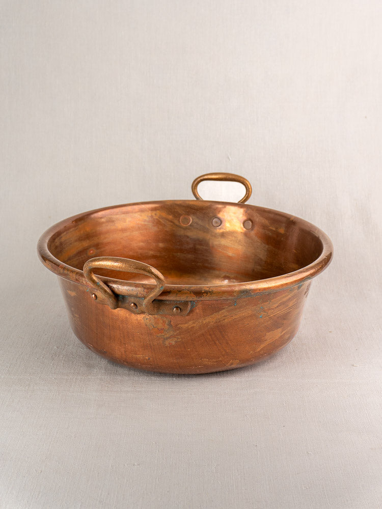 Pair of late 19th-century French copper basins with handles, displayed on light fabric.