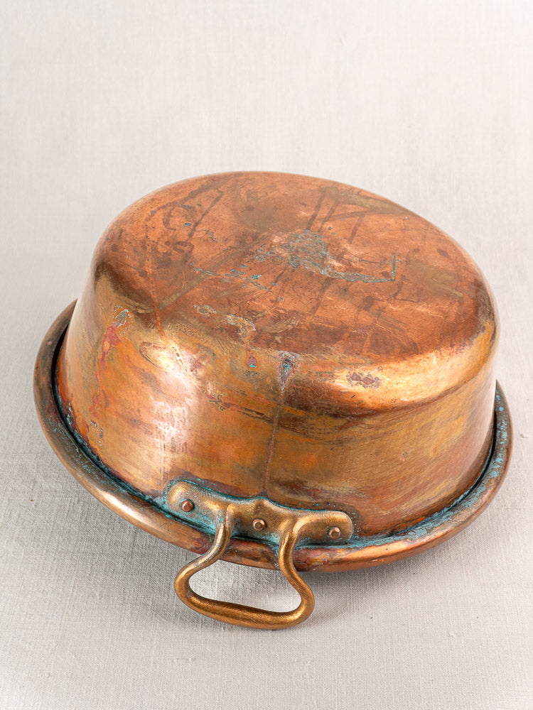 Antique French copper basin, late 19th century, upside down with patinated handle and visible oxidation.