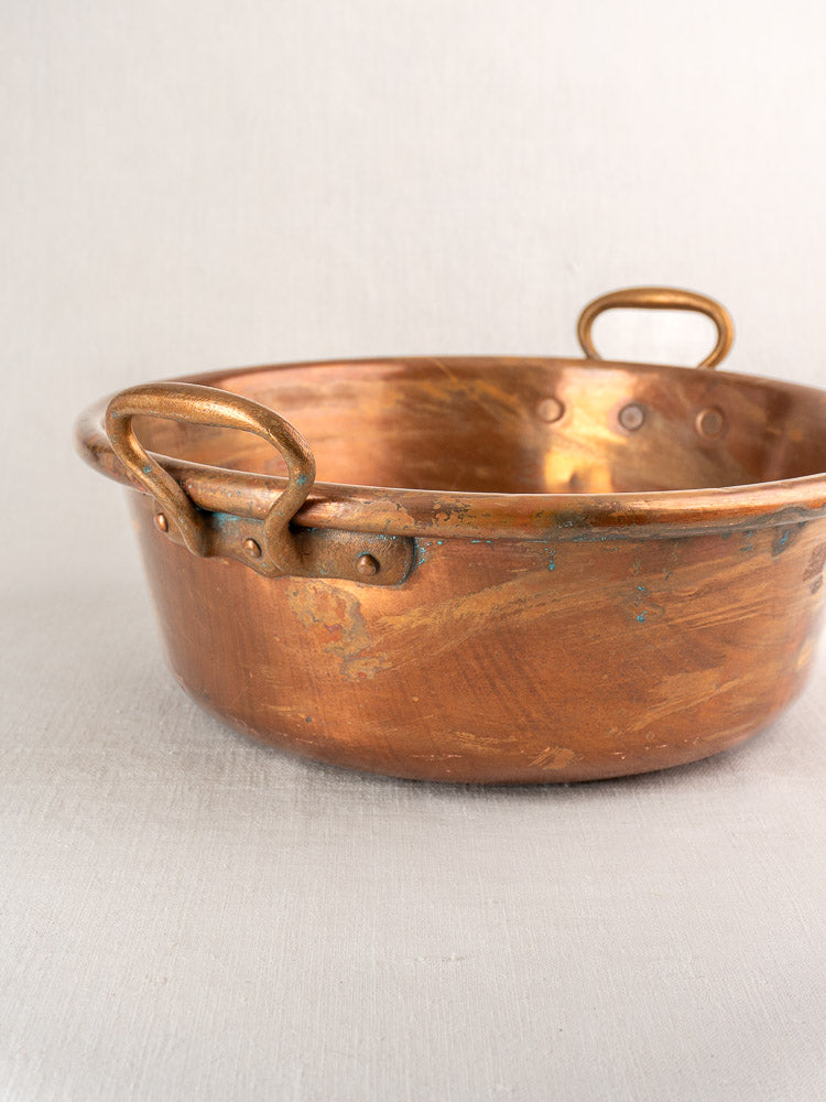 Pair of late 19th-century antique French copper basins with sturdy handles on light fabric background.