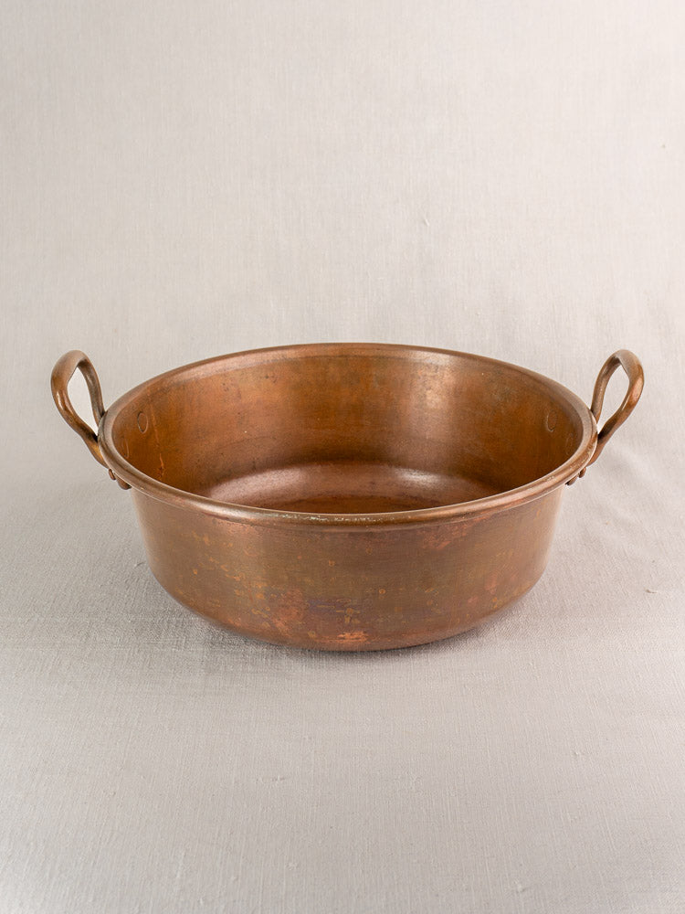 Pair of antique French copper basins with curved side handles and shallow, round nesting design. Late 19th century.