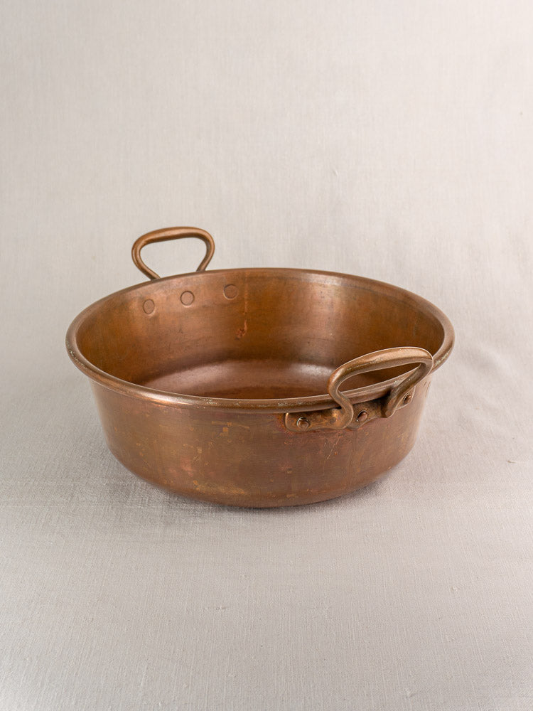 Pair of late 19th-century antique French copper basins with looped side handles, nested on light fabric.