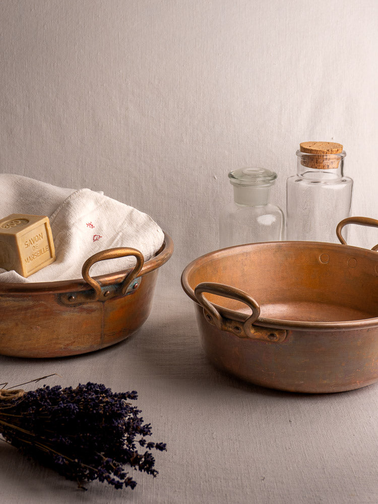 Pair of late 19th-century French copper basins, one with towels and soap, styled with jars and dried lavender.