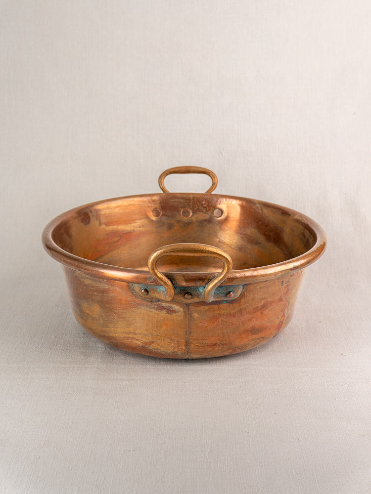 Pair of late 19th-century French copper basins with side and top handles, aged patina, plain background.