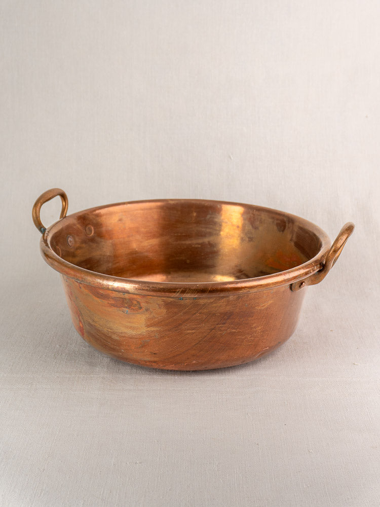 Pair of antique French copper basins with handles on light gray fabric, Nesting Pair collection.