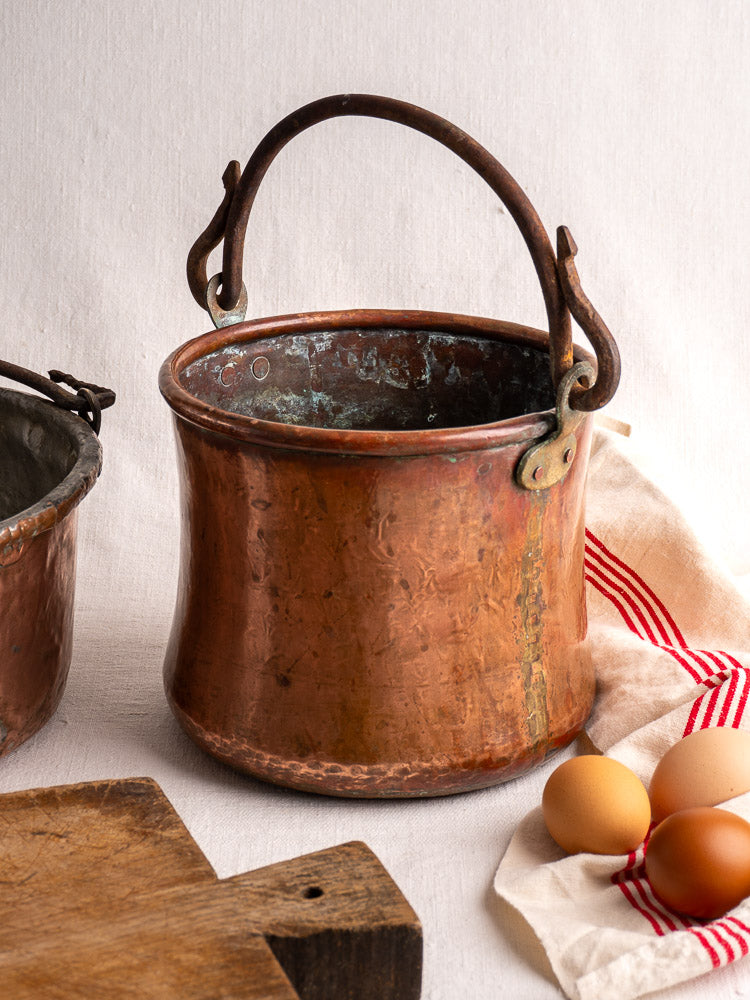 Antique French hammered copper bucket with wrought iron handle, displayed with eggs and a cutting board.