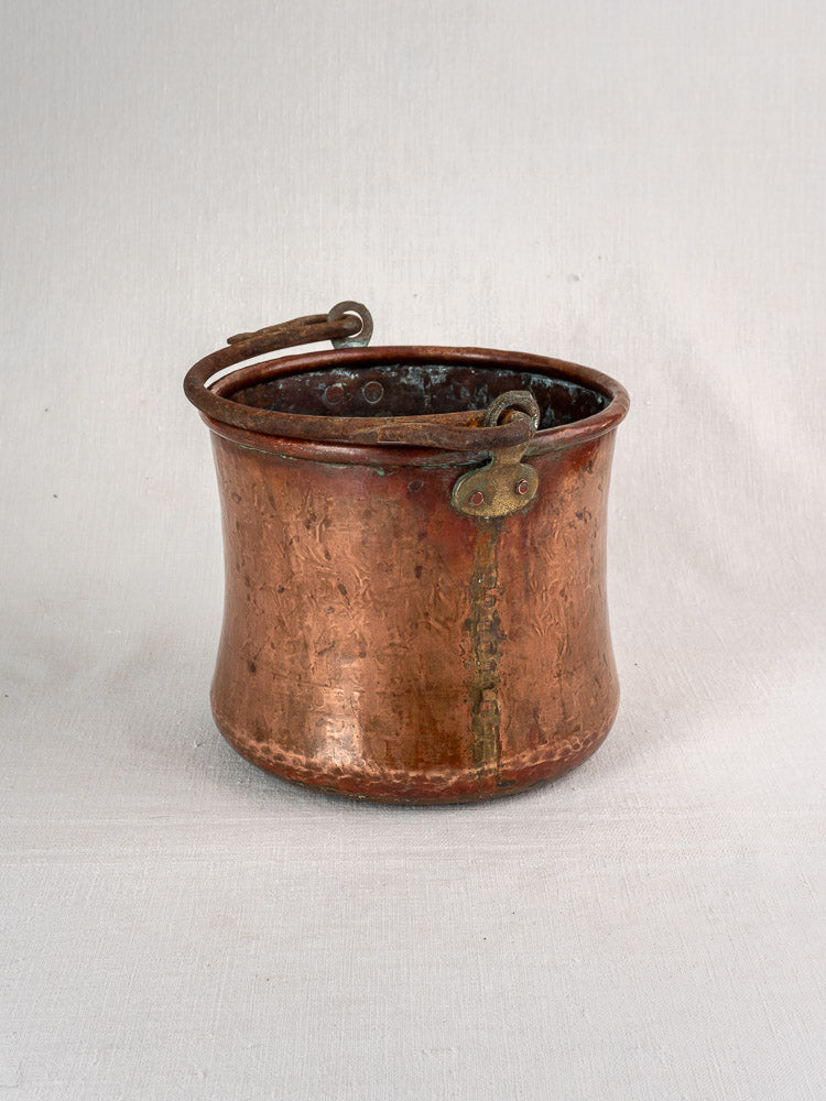 Antique French hammered copper bucket with wrought iron swing handle and latch, lightly tarnished.