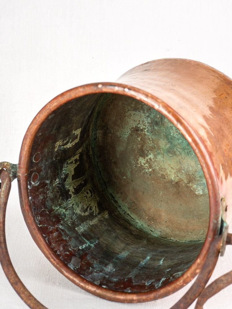 Antique French hammered copper bucket with green patina, interior corrosion, and wrought iron swing handle.
