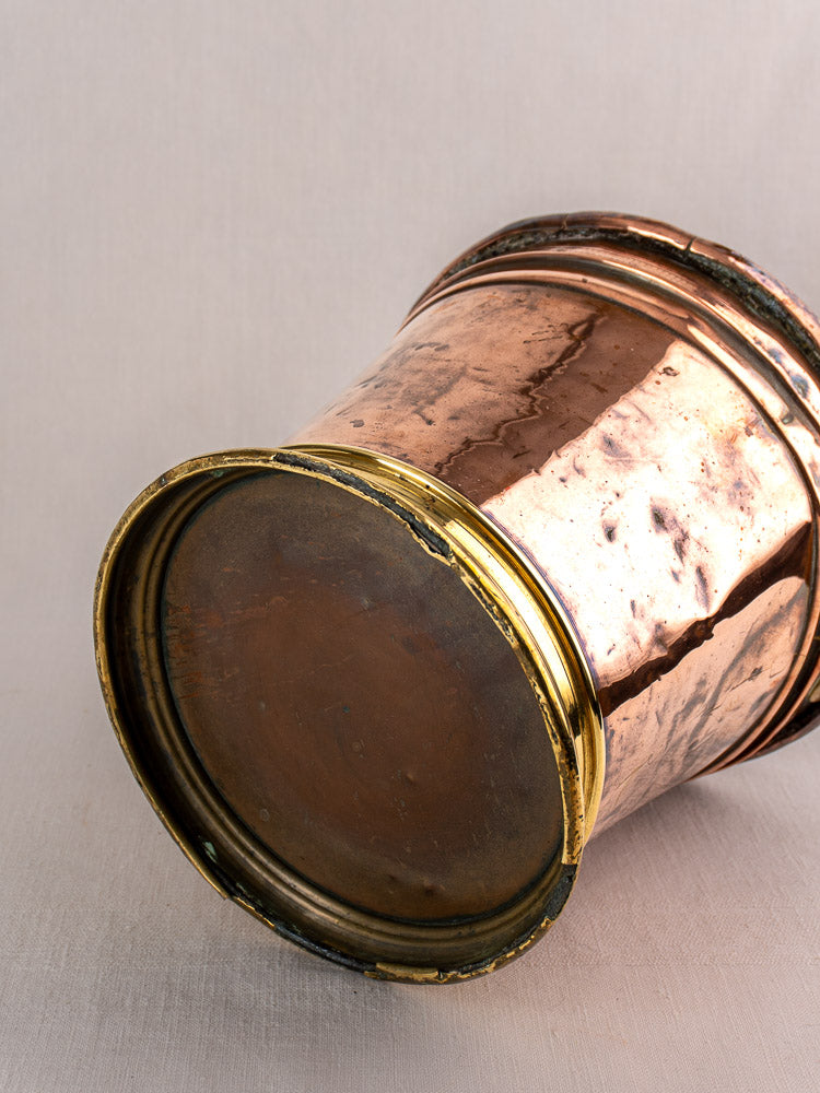 Antique French copper champagne bucket with gold-toned rim and aged copper patina on a neutral backdrop.