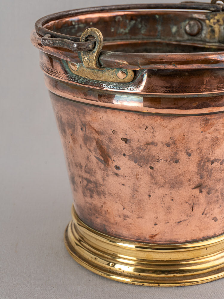 Antique French copper champagne bucket with brass base and handle, late 19th century, rustic patina, on light background.