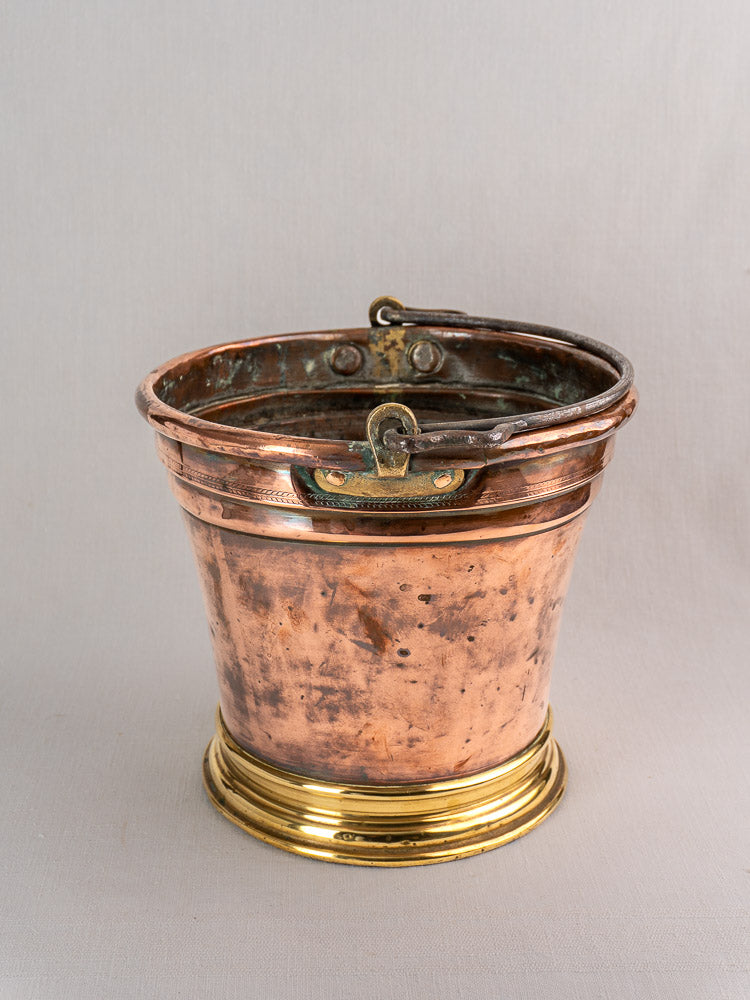 Antique French copper champagne bucket with brass handle, polished base, and aged patina on a light gray background.