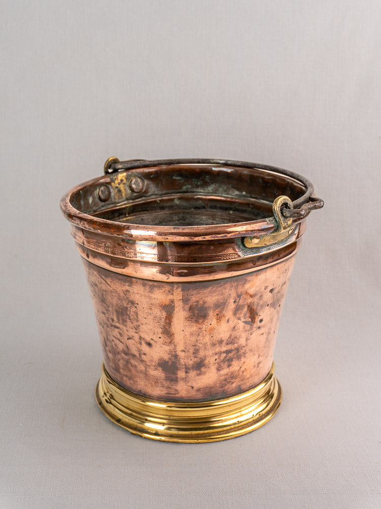Late 19th century French copper champagne bucket with brass base, tarnished finish, and two handles on light gray background.