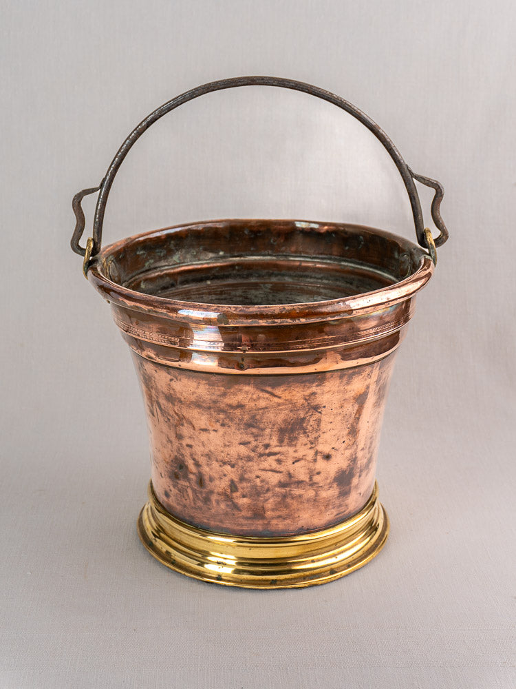 Late 19th-century French copper champagne bucket with dark metal handle and brass base on light gray background.