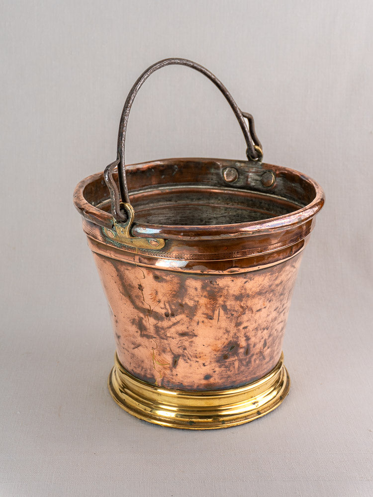 Antique French copper champagne bucket with brass base and metal handle, featuring aged patina and rustic charm.