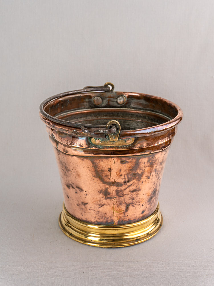 Late 19th century French copper champagne bucket with brass base and hinged latch, tarnished for rustic appeal on light background.