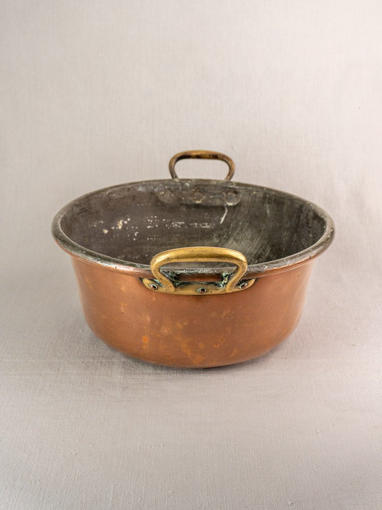 Late 19th-century French copper jam pan with brass handles and worn, darkened interior.