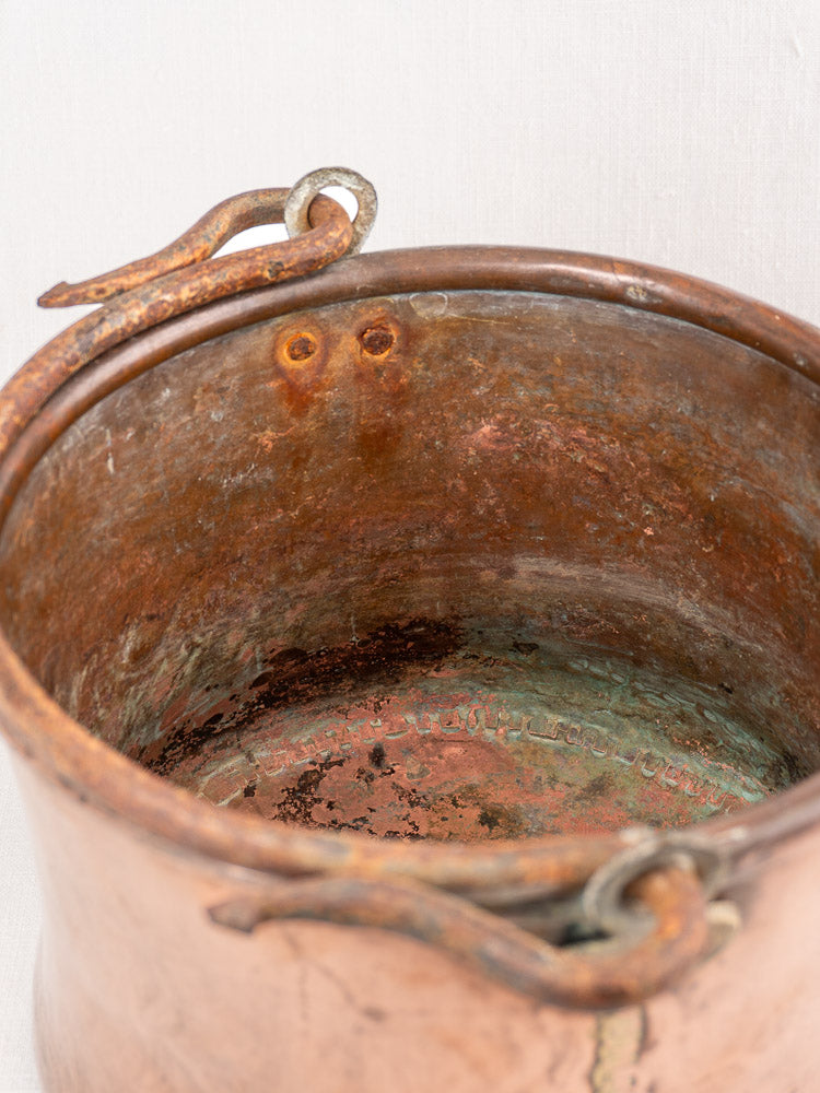 Antique French copper cauldron, hammered surface, iron bail handle, worn rim, greenish patina, vintage interior details.