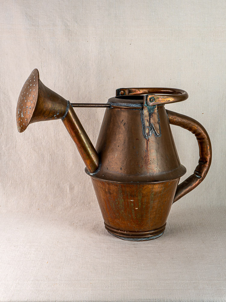 Vintage French copper watering can by Jean Goardère with large spout and handle on fabric.