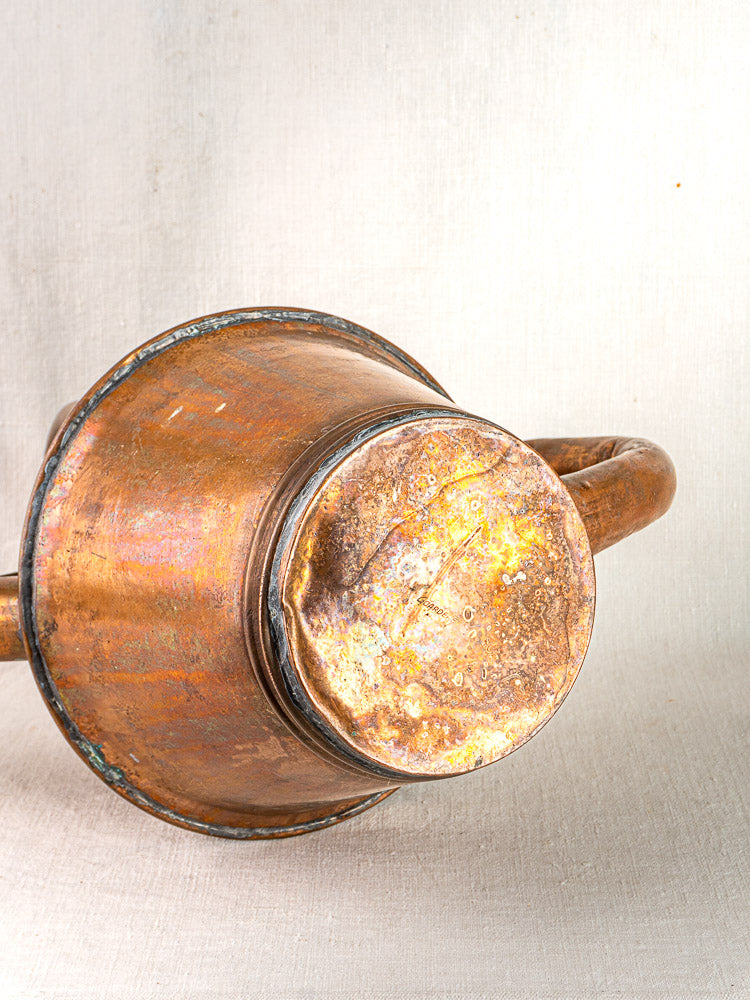 Vintage French copper watering can by Jean Goardère with round, dented base and curved handle.