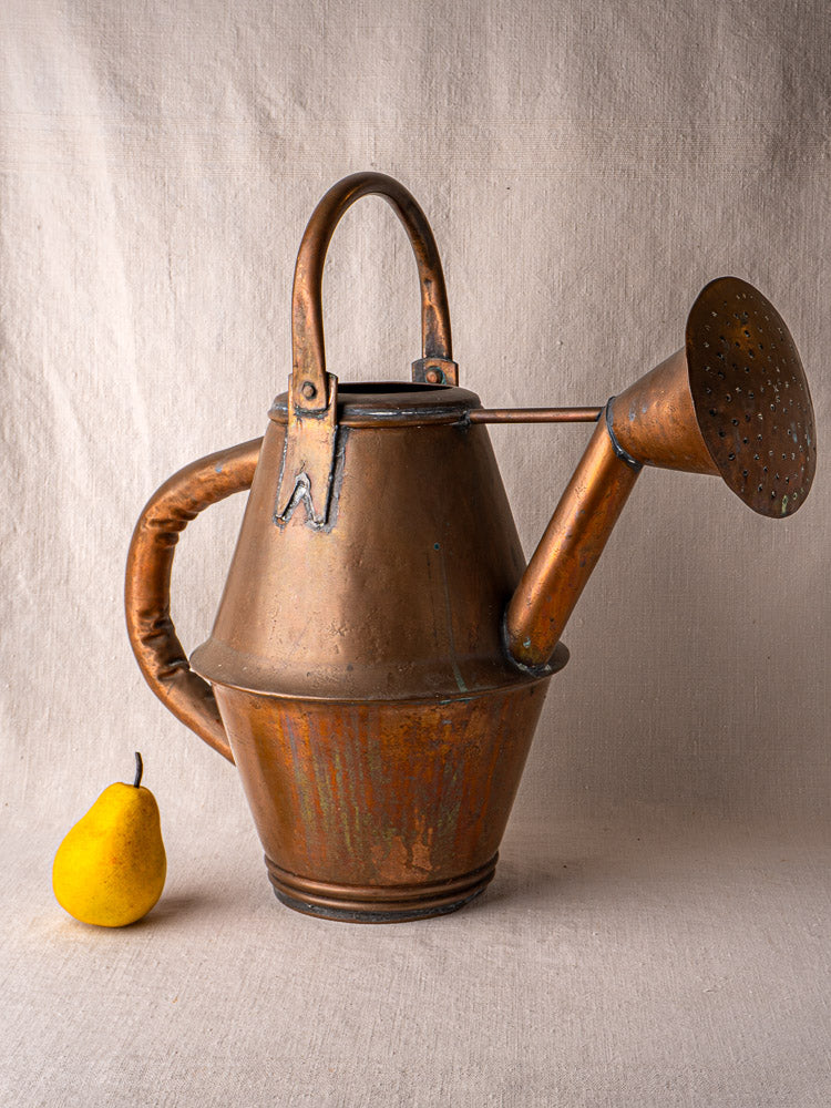 Vintage French copper watering can by Jean Goardère, Villedieu MOF, on beige cloth with yellow pear.
