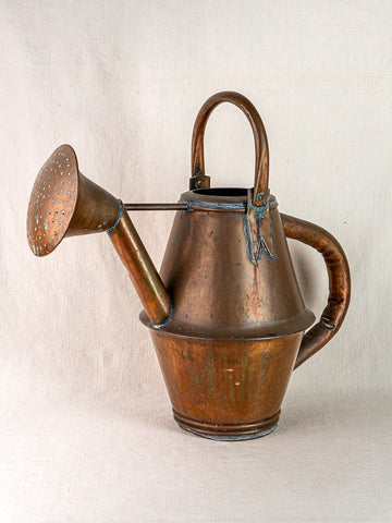 Vintage French copper watering can by Jean Goardère with wide spout and large handle on light fabric.