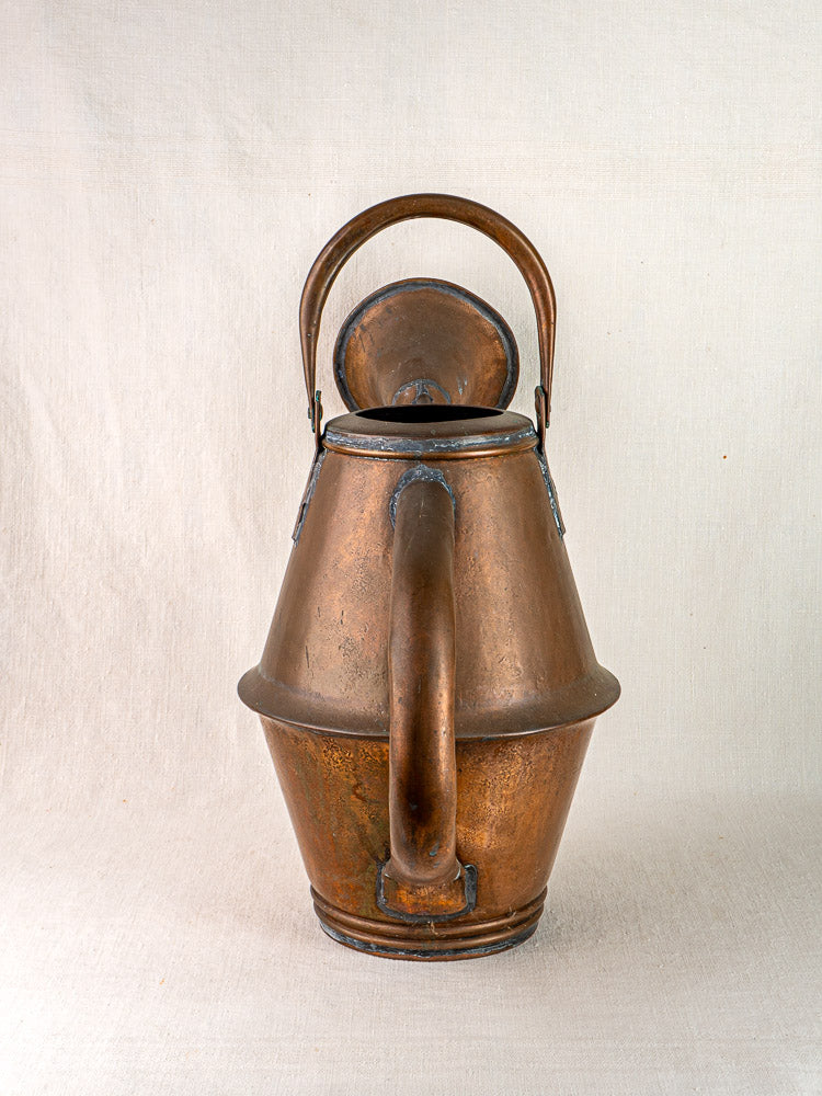 Vintage French copper watering can by Jean Goardère, wide body and curved handle, on neutral fabric.