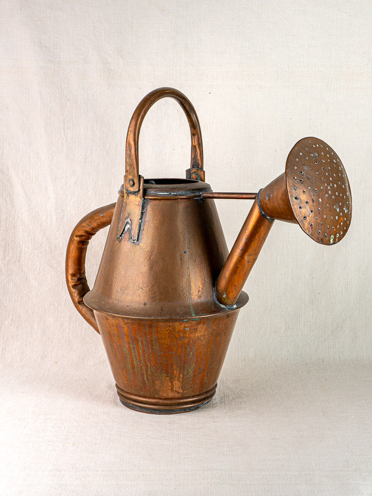 Vintage French copper watering can by Jean Goardère, Villedieu MOF, on a light fabric background.