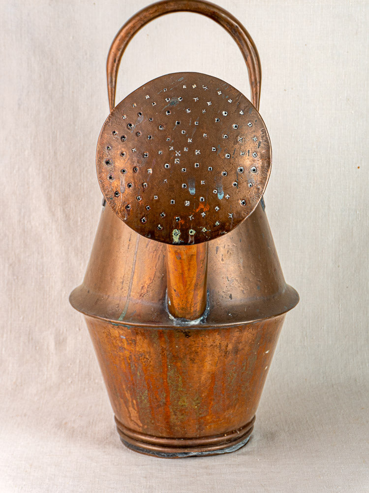 Vintage French copper watering can by Jean Goardère, Villedieu MOF, with large spout and perforated rose on beige fabric.