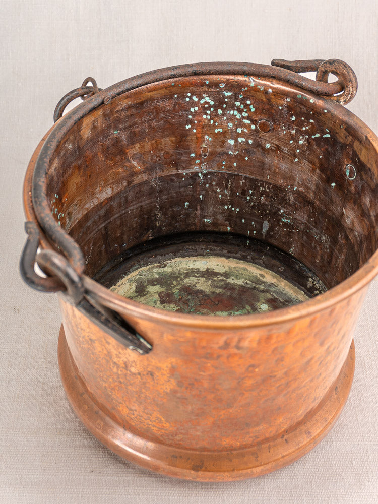 Pair of 19th-century French antique copper hanging buckets with iron handles, green patina; shown on light fabric surface.