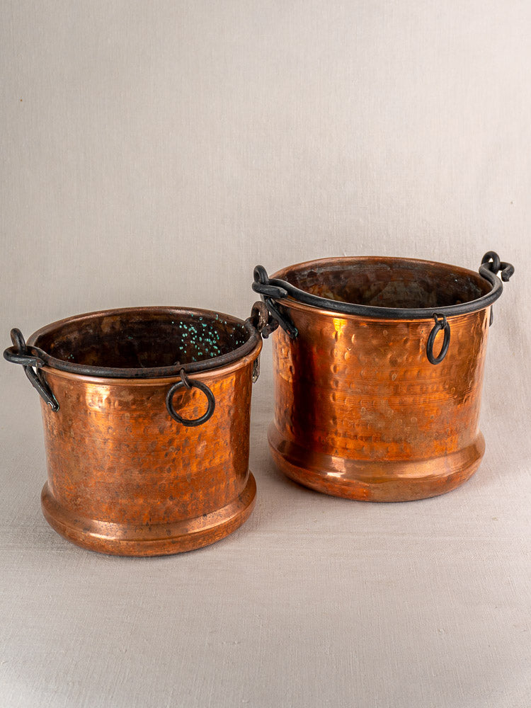 Pair of 19th-century French copper hanging buckets with black metal handles, side by side on neutral fabric.