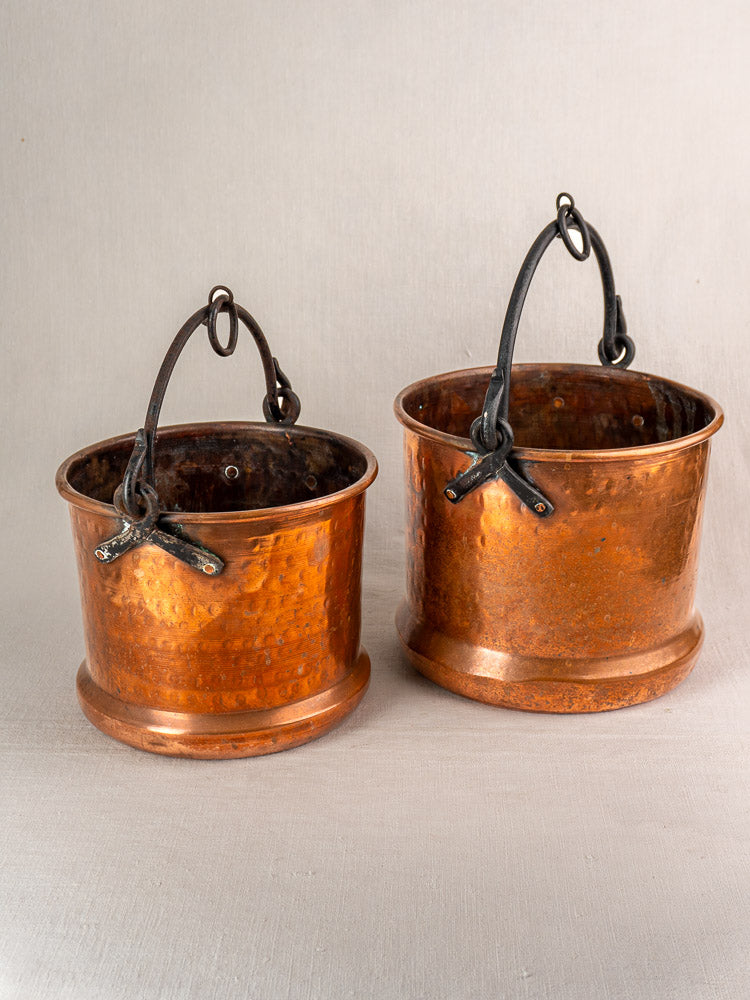 Pair of 19th century French copper hanging buckets with black metal handles, textured sides, and flared bases.