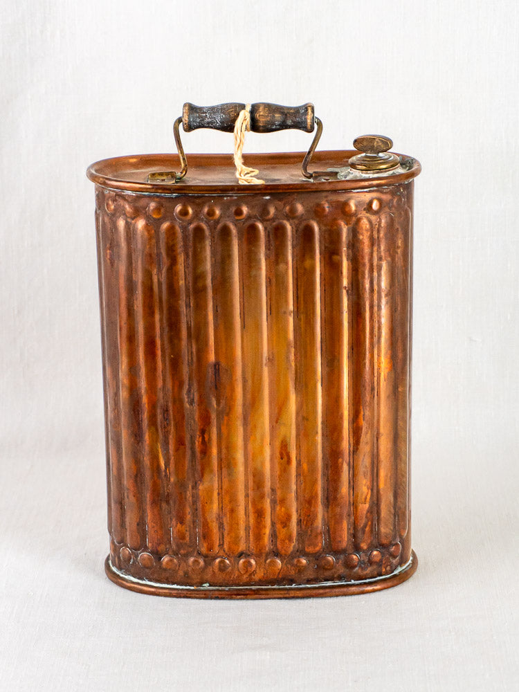 Vintage French copper bouillotte hot water bottle with ribbed design, black wooden handle, and round screw cap.