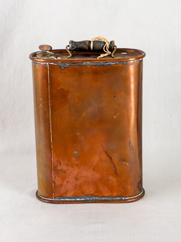 Vintage French bouillotte-style copper hot water bottle with fluted design, screw cap, black wooden handle.