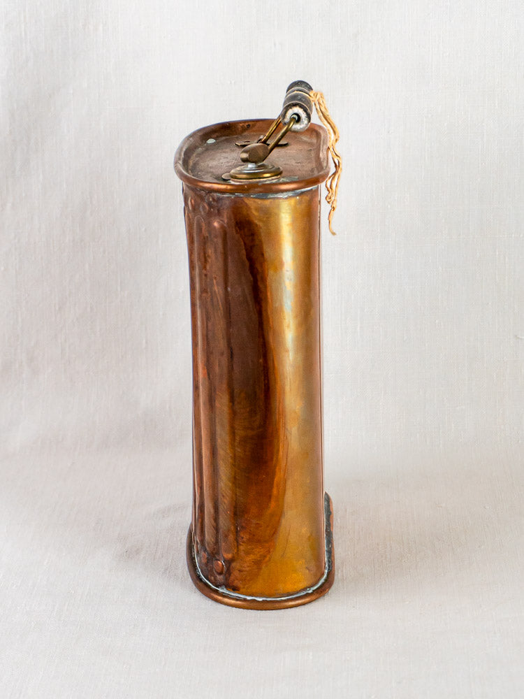 Vintage French copper Bouillotte hot water bottle with fluted design on a light surface.