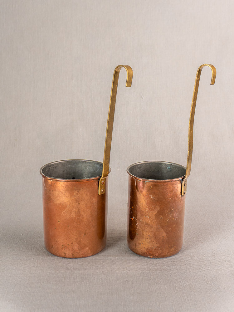 Set of 5 antique French copper measures with curved brass handles and aged patina, arranged on a neutral background.