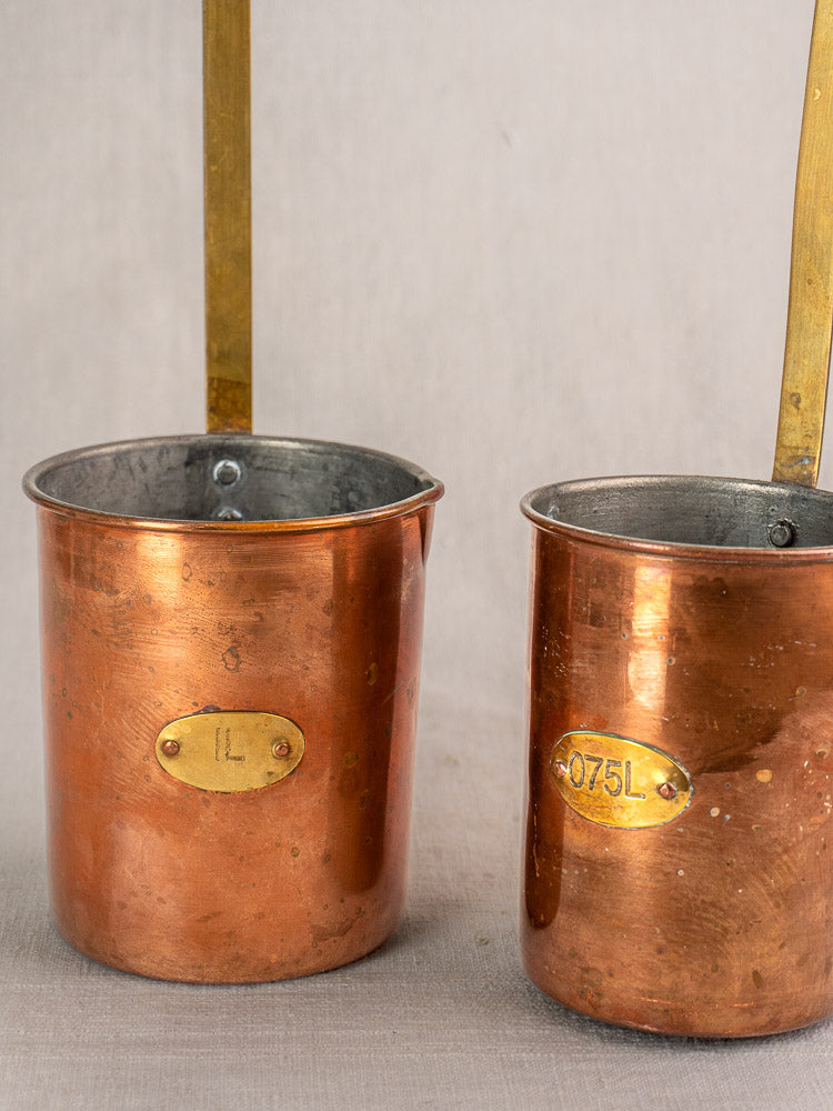 Antique French copper measure set of five with brass handles and volume labels, late 19th century.