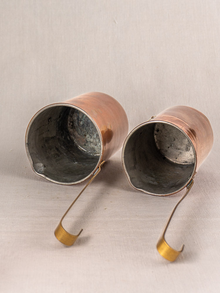 Set of five late 19th century antique French copper measures with worn interiors on a light beige surface.