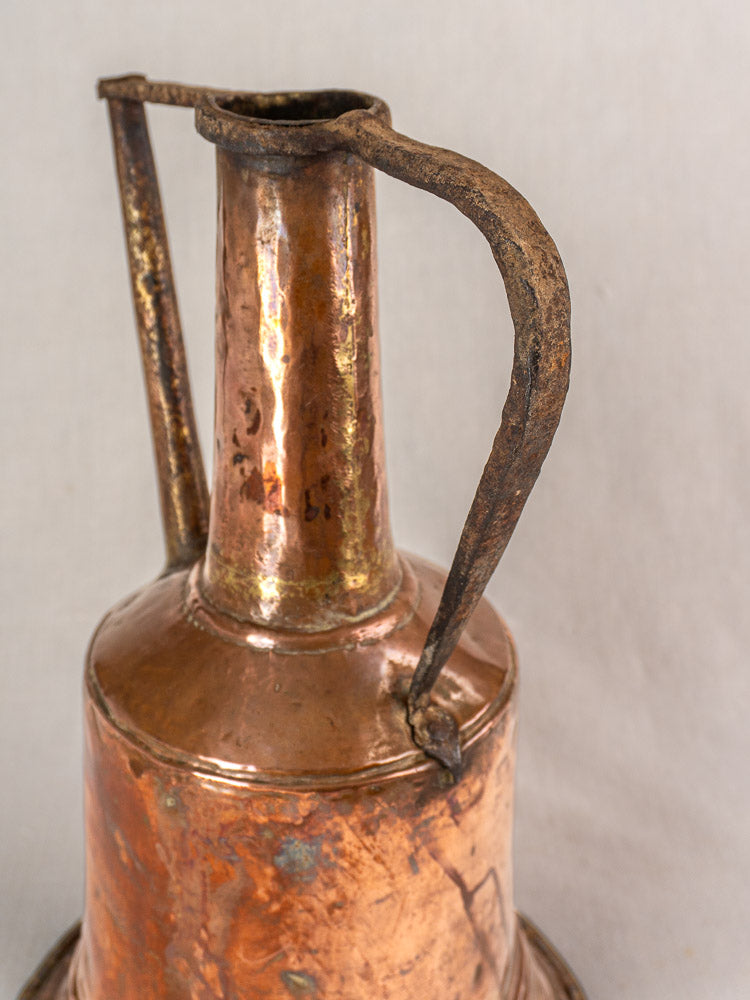 Antique French copper water jar with hammered finish and twin iron handles, set against a plain light background.