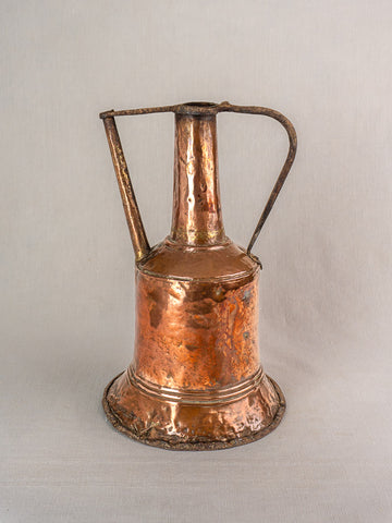 19th-century French copper water jar with iron handles and hammered finish on a light gray fabric background.