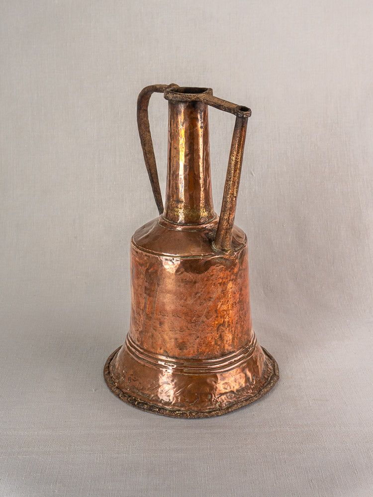 Antique French hammered copper water jar with wide base, narrow neck, twin iron handles on light gray background.