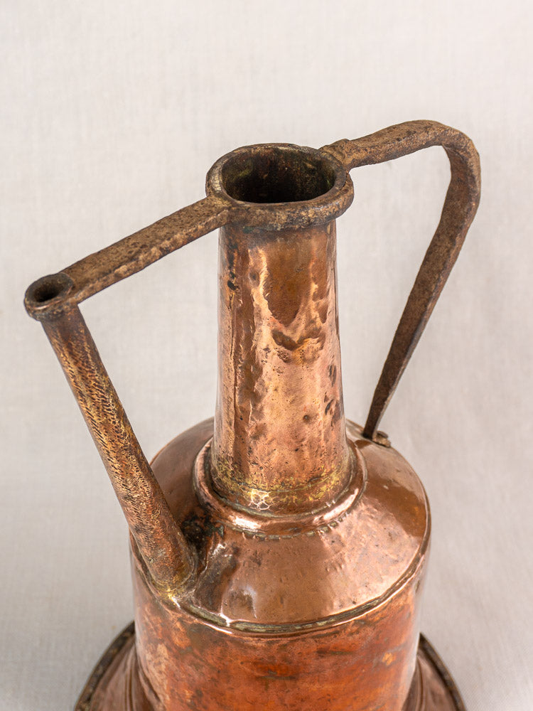Antique French hammered copper water jar with tall neck and twin iron handles on a plain light background.