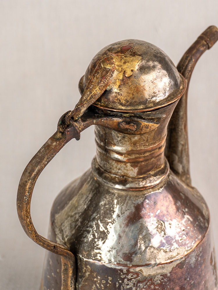Antique French copper oil jug with domed lid, curved spout, handle, and aged patina on light background.