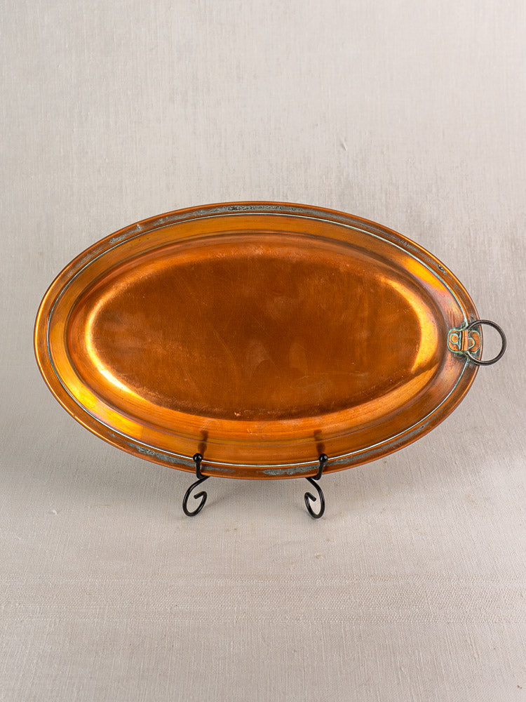 Antique French copper platter, oval tinned dish with metal rim and hanging ring, displayed on a black stand.