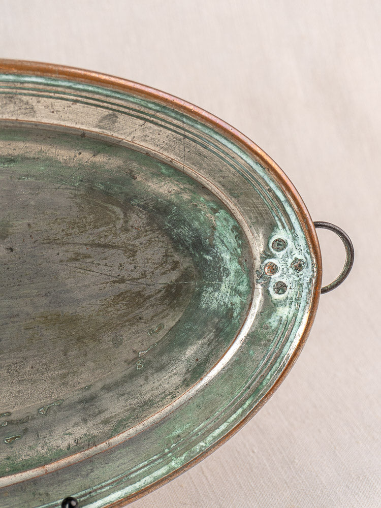 Antique French copper platter, tinned oval dish with rivets and hanging ring on neutral fabric background.