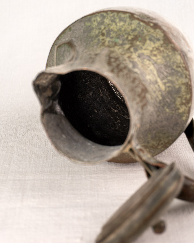 Antique French metal teapot with hinged lid open, tarnished surface, and dark interior exposed.