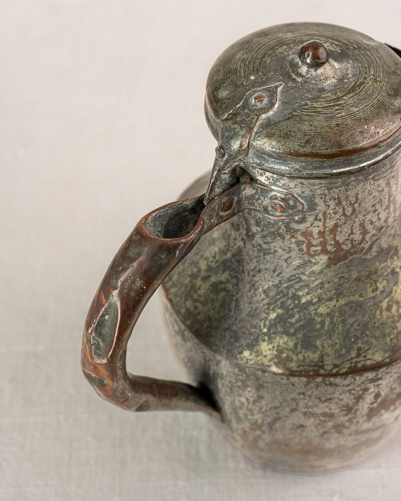 Antique French copper pitcher by Allez Frères Paris with hinged lid, curved handle, aged patina on neutral fabric.