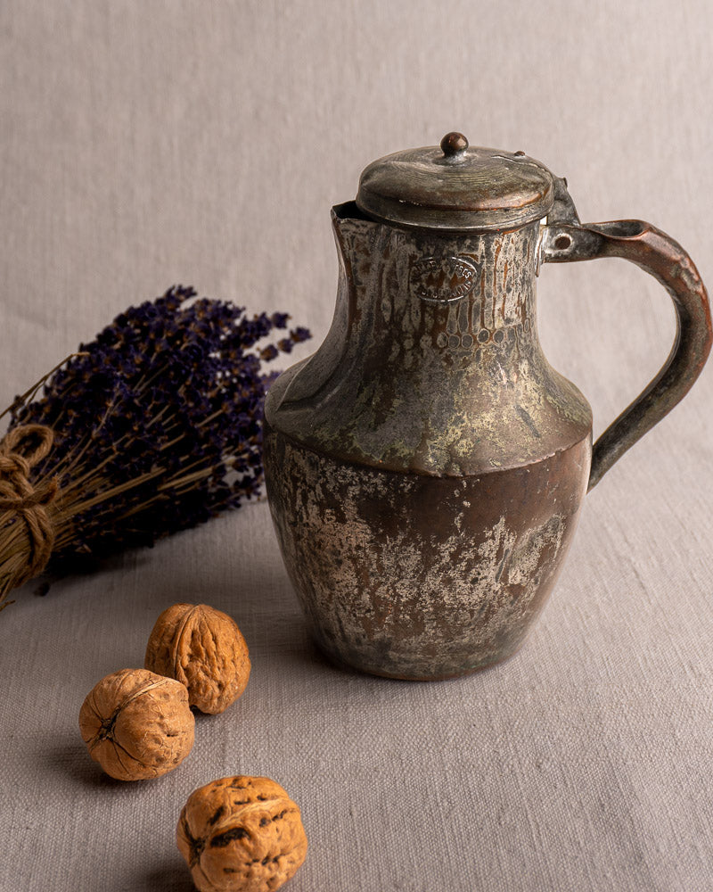 Antique French copper Coquemar pitcher by Allez Frères Paris with hinged lid, walnuts, and dried lavender on beige cloth.