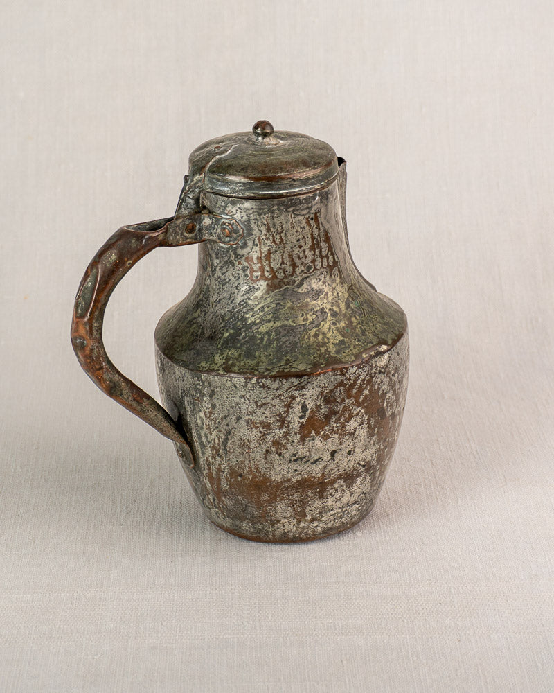 Antique French copper pitcher by Allez Frères Paris with hinged lid and curved handle on light textured surface.