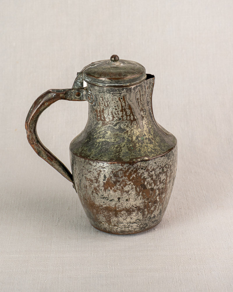 Antique French copper pitcher by Allez Frères Paris with curved handle and hinged lid on fabric.