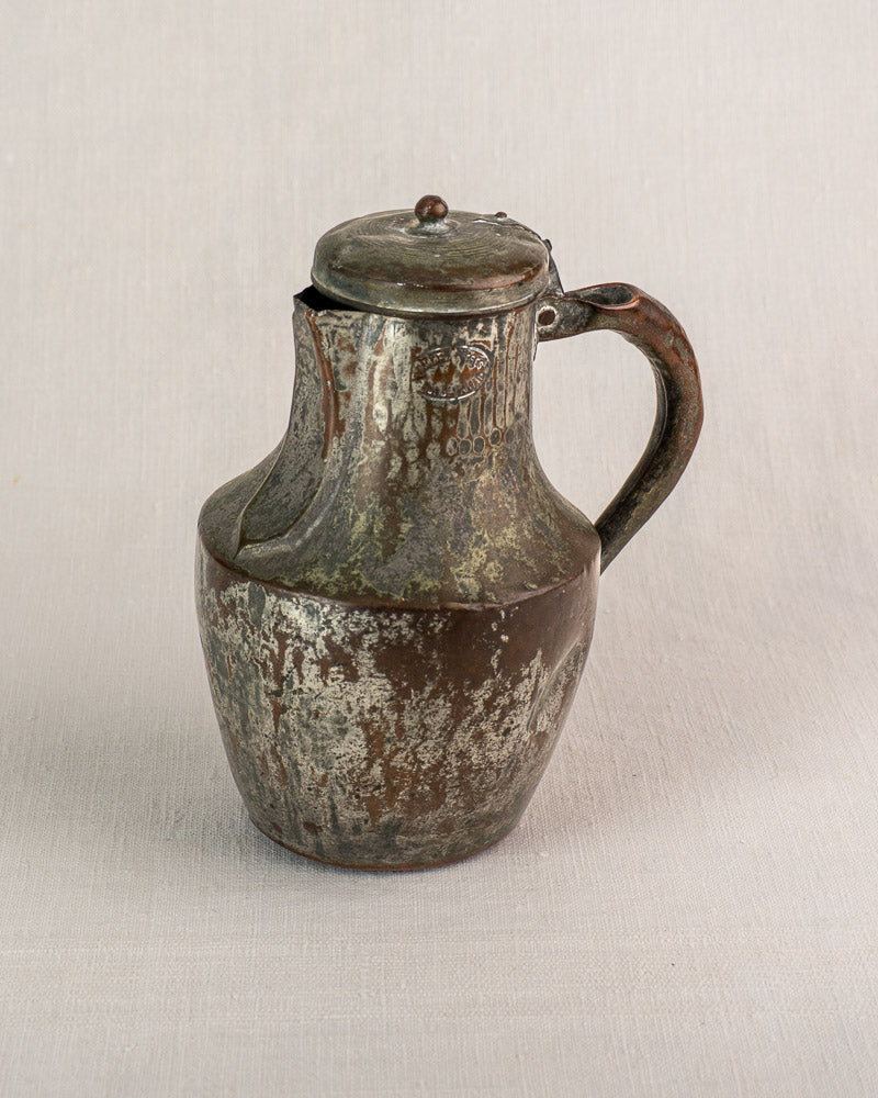 Antique French copper pitcher by Allez Frères Paris with hinged lid and curved handle on light fabric background.